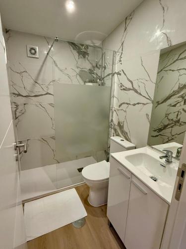 a white bathroom with a toilet and a sink at GuestHouse Bragas Porto Center in Porto
