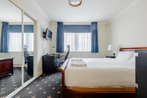 a hotel room with a bed and a desk and a mirror at Hestia Travel London in London