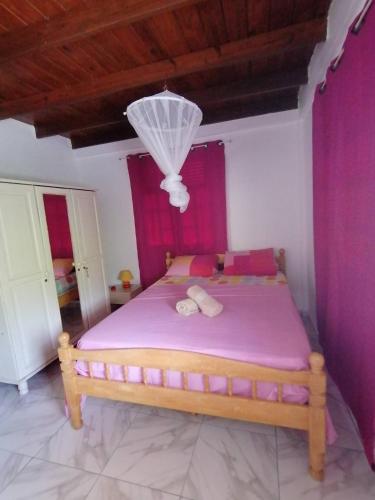 una camera da letto con un letto con lenzuola rosa e un lampadario di Villa Océane a Dublanc