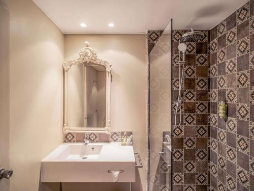 a bathroom with a sink and a mirror and a shower at Hotel Mercure Parc du Coudray - Barbizon in Le Coudray-Montceaux