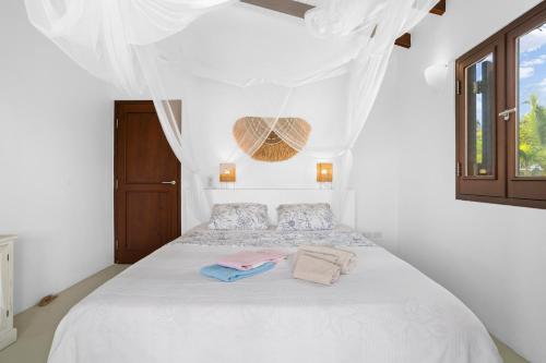 Schlafzimmer mit einem weißen Bett und weißen Vorhängen in der Unterkunft Kas Palma at Waterland's Village - Private pool! in Kralendijk