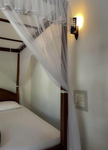 a bedroom with a bed with a mosquito net at Mermaid Inn in Mirissa