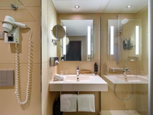 a bathroom with a sink and a mirror at Mercure Hotel Hannover City in Hannover