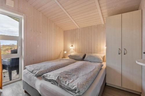 une chambre avec un grand lit et une fenêtre dans l'établissement Skipper-Lodge Nord, à Hestoft