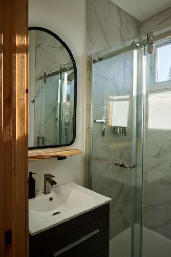 a bathroom with a sink and a shower with a mirror at Horizon - plein air et détente in Lac-Beauport