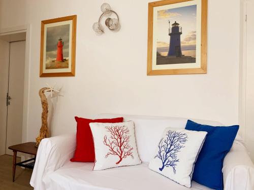 Un sofá blanco con almohadas rojas y azules. en Tina Piano Terra, en Castiglione della Pescaia