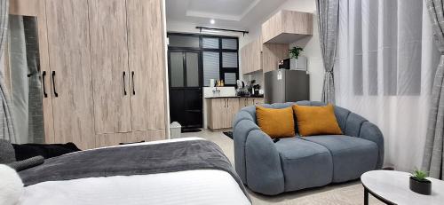 a living room with a blue couch and a kitchen at Bliss Stay Ruaka in Ruaka