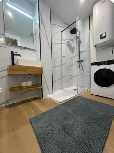 a bathroom with a shower and a sink and a microwave at Alojamiento con encanto in Santoña