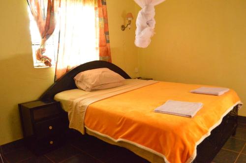 a bedroom with a bed with an orange blanket and a window at EKO Holiday Homes, Lake Chala in Chala