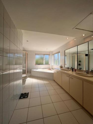 a large white bathroom with two sinks and mirrors at 2 on Aurora Island in Durbanville