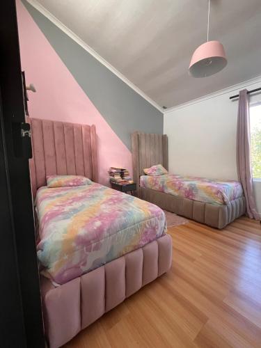 a bedroom with two beds and a pink wall at 2 on Aurora Island in Durbanville