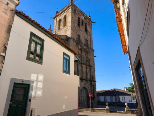a church with a clock tower in a street at Casa do Adro in Torre de Moncorvo