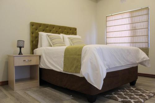 BroadhurstにあるStaybridge Apartments Francistownのベッドルーム(大型ベッド1台、ナイトスタンド付)