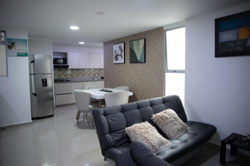 a living room with a black couch and a kitchen at Apartamento Central Parque de Sabaneta-901 in Sabaneta