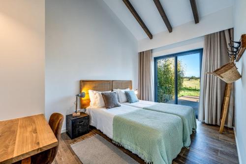 ein Schlafzimmer mit einem Bett und einem Tisch und einem Fenster in der Unterkunft Monte da Fonte in Zambujeira do Mar