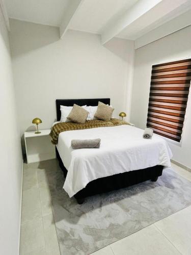 a bedroom with a large bed and a window at 44 Staycation Beach-house in Britannia Bay