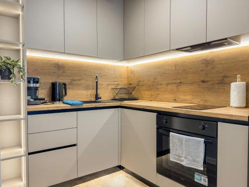 a kitchen with white cabinets and a black oven at 2BР Apartment in a Modern Complex in Plovdiv