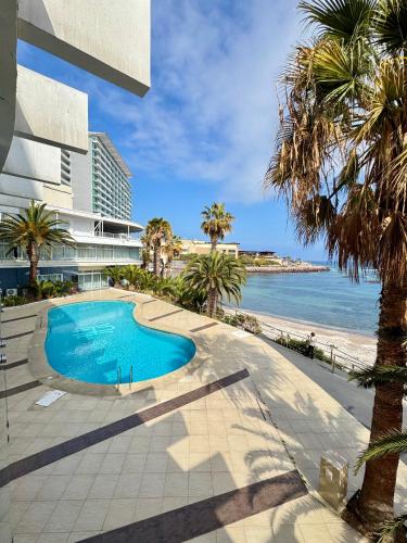 una piscina accanto a una spiaggia con palme di Hotel Antofagasta ad Antofagasta