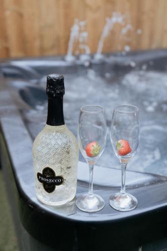 a bottle of wine and three wine glasses on a tray at Marine Cottage 1 - With Private Hot Tub in Newbiggin-by-the-Sea