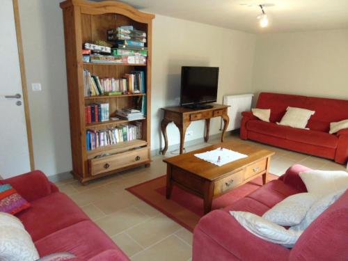 ein Wohnzimmer mit zwei roten Sofas und einem TV in der Unterkunft Gîte Les Hervelines in Le Val Hervelin