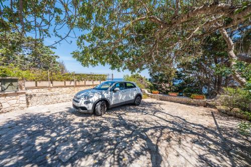 a car parked on a dirt road under a tree at Villa fronte mare nel Salento in Castro di Lecce