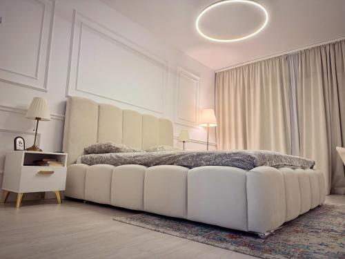 una camera bianca con un grande letto bianco e un tavolo di Boutique Apartment 2 a Ploieşti
