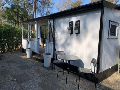 a small white shed with a table and chairs at Celisa S Häuschen in Hoenderloo