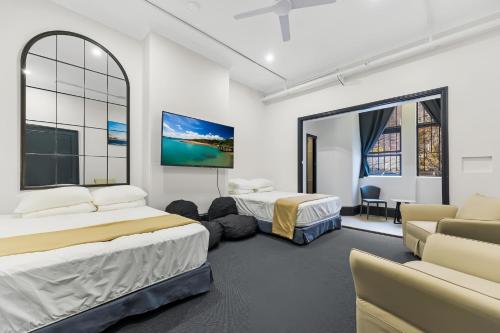 a room with two beds and a couch and a tv at London Gate Backpackers Hotel in Sydney