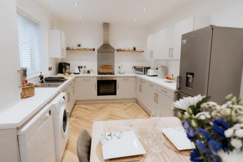 eine Küche mit weißen Schränken und einem Tisch in der Unterkunft Marine Cottage 2 - With Private Hot Tub in Newbiggin-by-the-Sea