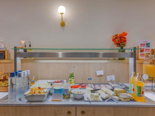 Una mesa con un montón de comida en un mostrador. en Mercure Lyon Est Villefontaine, en Villefontaine