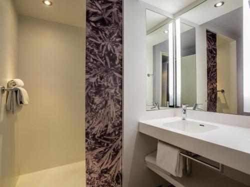 une salle de bain avec un lavabo et un miroir dans l'établissement Mercure Marseille Centre Vieux Port, à Marseille