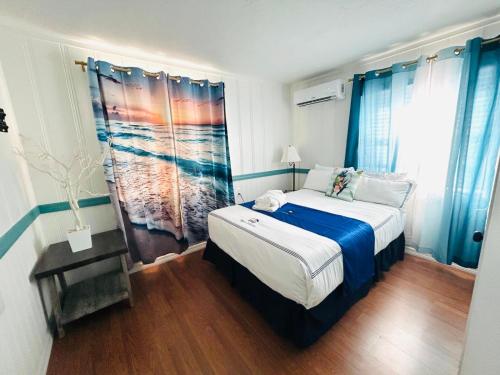 a bedroom with a large bed with blue curtains at Playa Esmeralda Cottage! Add Golf Cart!! in Bradenton Beach