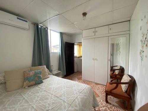 Un pequeño dormitorio con una cama y una silla. en Los Tamarindos Posadamanabita, en Portoviejo