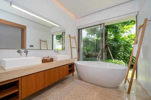 une salle de bain avec une grande baignoire et une grande fenêtre dans l'établissement Anchan Tropicana 4 bedroom near Beach, à Phuket