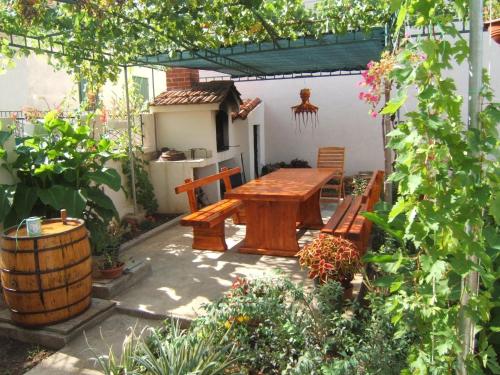 un patio con mesa de madera y bancos en un jardín en Kleines Apartment Emil Vanily, en Murter