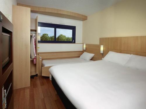 a hotel room with two beds and a television at ibis Poitiers Site du Futuroscope in Chasseneuil-du-Poitou