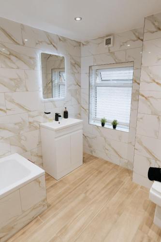 a white bathroom with a sink and a mirror at Marine Cottage 2 - With Private Hot Tub in Newbiggin-by-the-Sea
