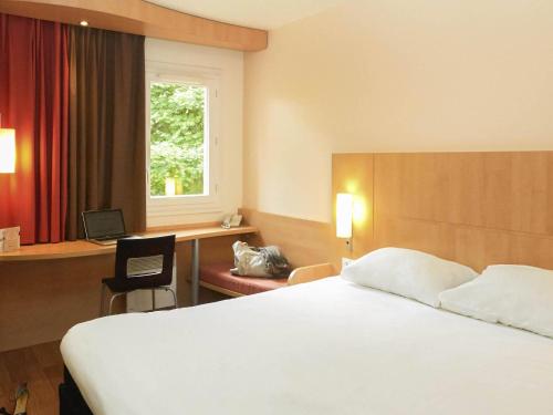 シストロンにあるibis Sisteronのベッドと机と窓のあるホテルの部屋