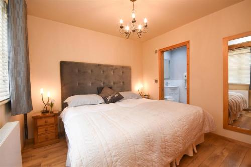 ein Schlafzimmer mit einem großen Bett und einem Kronleuchter in der Unterkunft The Barn in Little Maplestead