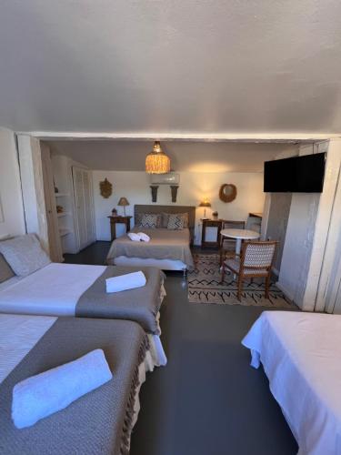 a hotel room with three beds and a television at Vila alecrim Guest House in Búzios
