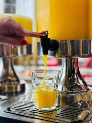 a person is making a glass of orange juice at Hotel Ibis Tatui in Tatuí