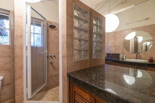 a bathroom with a shower and a sink and a mirror at Pool House Studio by YourHost Karen Nairobi in Nairobi