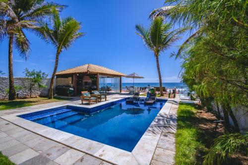 a swimming pool with palm trees and the ocean at Mar a Vista Charme by Concavus in Porto De Galinhas