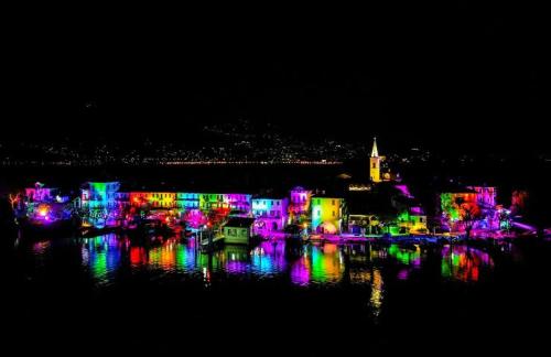 une ville illuminée la nuit avec des lumières dans l'eau dans l'établissement Villetta Primavera, à Verbania