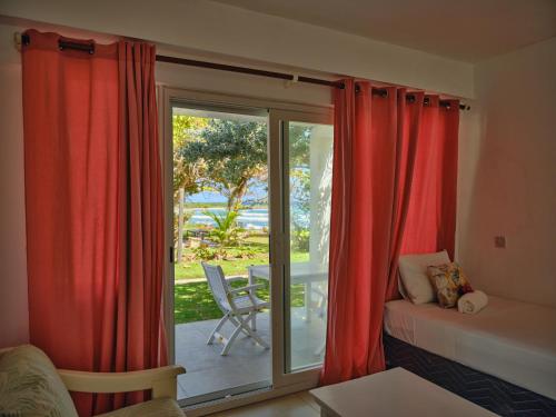 Ocean Spray Apartments في كرايست تشيرش: غرفة معيشة مع ستائر حمراء وباب زجاجي منزلق