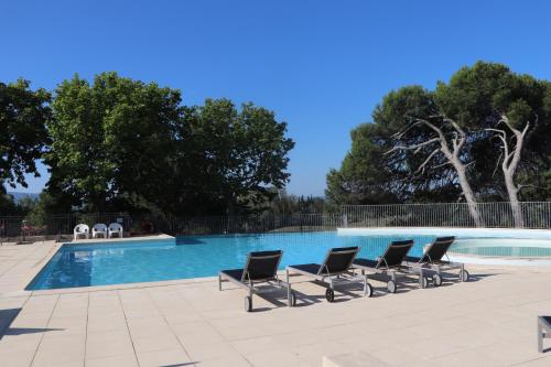 a row of lounge chairs next to a swimming pool at Greens View golf saumane in Saumane-de-Vaucluse