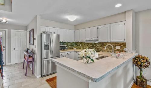 une cuisine avec des armoires blanches et un réfrigérateur en acier inoxydable dans l'établissement Retreat with Creekside Patio Snowmass Village, à Snowmass Village