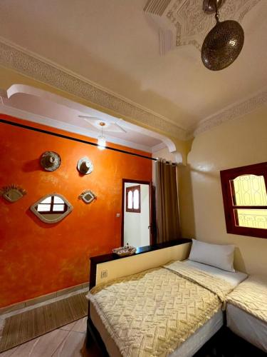 a bedroom with a bed with an orange wall with eyes at Dar Zina in Aourir