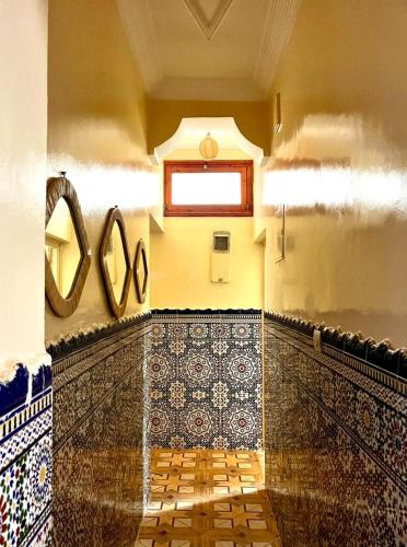 a bathroom with mosaics on the wall and a mirror at Dar Zina in Aourir