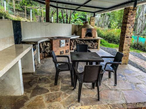 d'une terrasse avec une table, des chaises et un four extérieur. dans l'établissement Piscina Privada, Zona parrillas, 8 min del Pueblo, Parqueadero Cubierto, à Pacho